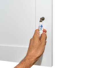 Left hand opens the cabinet door over white
