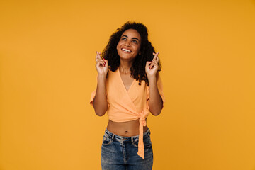 Black young woman smiling while holding fingers crossed for best luck