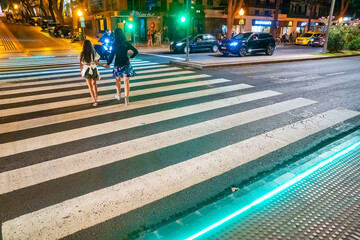Madeira, Portugal - September 3, 2022: Woman crossing mai street of Funchal with her daughter at night