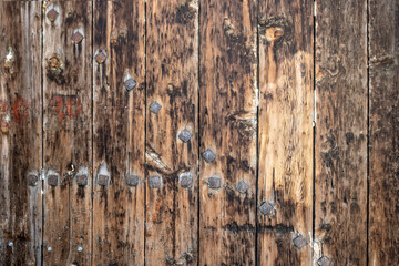 An old grungy, brown, unpainted, natural wood with grains and big metal nails for background and texture.