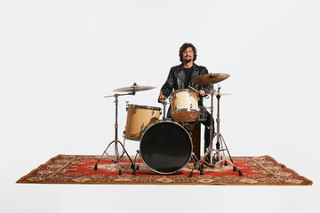 Studio shot of young musician with drums performing over white background. Concept of music, hobby,...