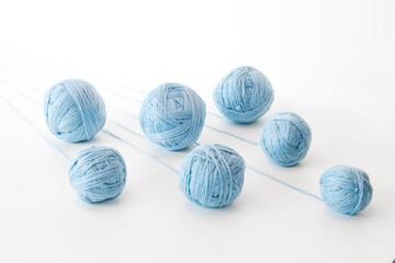 unwound threads from balls of blue yarn, on an isolated white background