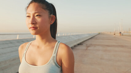 Asian girl in sports top walking outside at morning time