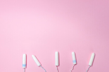 Many sanitary tampons lie in a row on a light pink background. Menstrual cycle and pregnancy. Negative pregnancy test and contraceptives