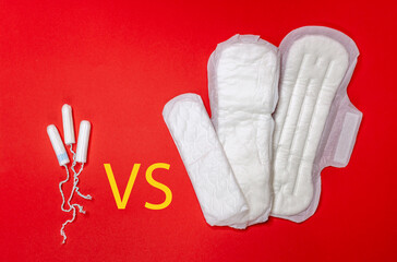 Three sanitary pads vs tampons lie on a red background. Menstrual cycle and pregnancy. Yellow inscription