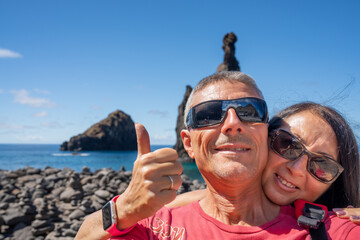 Happy couple taking selfie at Miradouro Ilheus da Ribeira da Janela. Rock formations above the sea, Madeira Island - Portugal