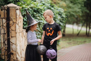 Little cute girl in witch costume and boy holding paper lanterns. Kids having fun on Halloween...