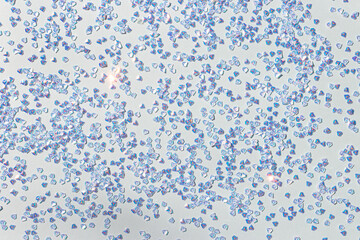 Silver crystal confetti on a blue pastel background. Glowing festive texture.