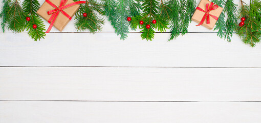 Fototapeta na wymiar Christmas background with fir tree branches red decorations and gift boxes on white wood banner.