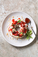 plate with bagel with mascarpone, strawberries and basil on the table