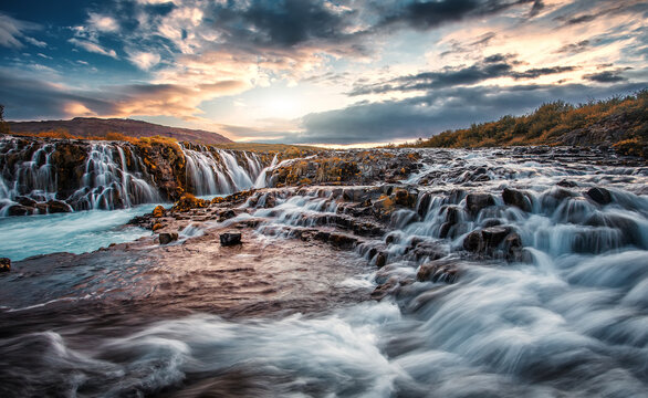 Scenic image of Iceland. Fantastic colorful sunset over the Bruarfoss Waterfall with picturesque sky. Wonderful Nature landscape. Iceland popular place of travel and touristic location.