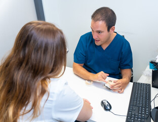 Dental clinic, dentist explaining to a client the teeth to be implanted in a model