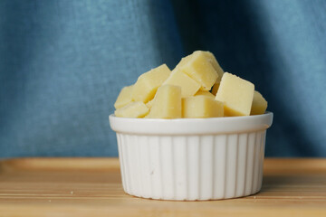 close up of cube shape fresh cheese on in a bowl 