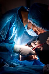 Dental clinic, dentist doctor and the assistant performing an oral operation in low light