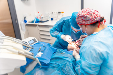 Dental clinic, dentists in blue suits performing an operation on an implant
