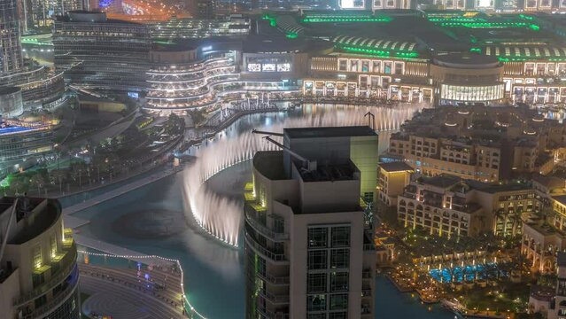 Dubai promenade singing fountains on the background of architecture with raditional houses in old town aerial timelapse. People watching show near shopping mall