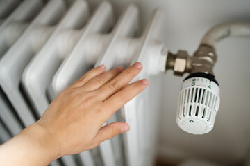 Rising heating costs in a crisis: people adjust the temperature in the house using a heating...