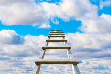 The way to success concept.Wooden ladder leading high up to the heaven.Blue sky and white clouds,...