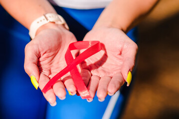 AIDS awareness.Caucasian woman hold red ribbon.Blurred background.World AIDS day concept.