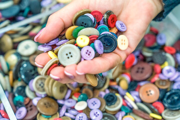 Woman hand choosing colorful buttons from a shelf