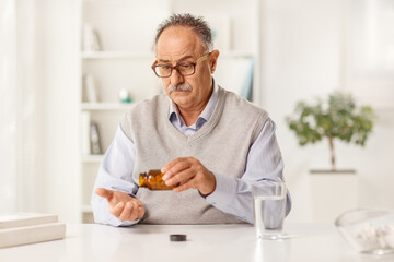 Pensive mature man at home taking pills