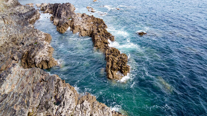 Beautiful sea waves break on the coastal rocks. White foam on turquoise water. Seascape on a sunny...