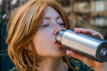 Portrait of a young woman drinking from a thermos