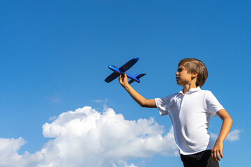 Child throwing toy plane. Boy playing with blue toy airplane against blue sky on sunny day outdoors