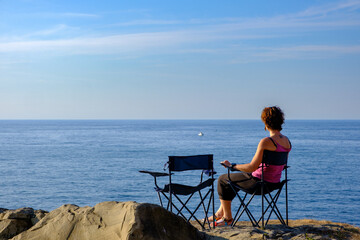 Ragazza si rilassa guardando l'Oceano nei pressi di Zumaia, Paesi Baschi, Golfo di Biscaglia, Mar...