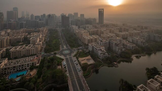 Skyscrapers in Barsha Heights district and low rise buildings in Greens district aerial night to day transition timelapse. Dubai skyline with morning fog during sunrise