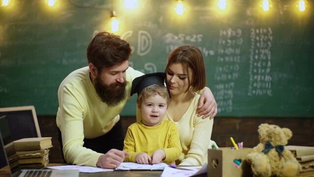 Young family studying and education. Young mother father and little preschooler boy sit at table drawing together, playing, painting pictures in notebook, early development.
