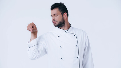 bearded man in chef jacket seasoning something isolated on white.