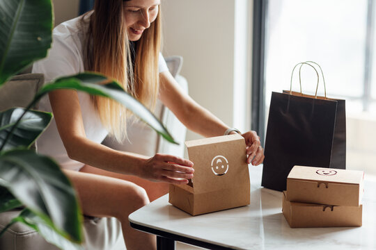 Young Caucasian Woman Unpacking Takeaway Paper Eco Bag As Food Delivery Courier Service At Home In Modern Apartment