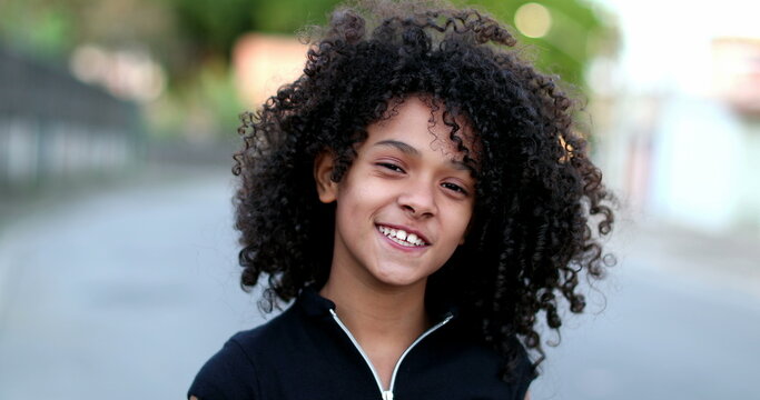 Black preteen girl smiling portrait. Brazilian mixed race child with curly hair face