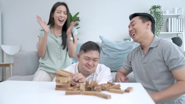 Happy Asian family doing activities together at home on vacation, Caring and encouraging special children, Down syndrome, Autism.