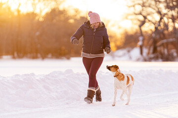 Woman jogging with dog in a winter snow storm. Fun winter exercise.