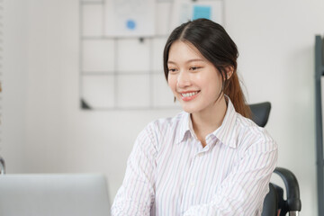 Happy attractive joyful asian woman working at workstation.