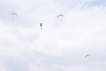 A paraglider group flying  on a cloudy day.