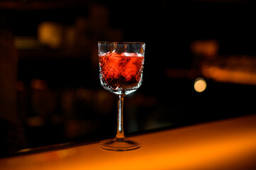 close-up perspective of crystal goblet with red alcoholic drink on bar counter