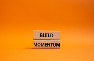 Build momentum symbol. Wooden blocks with words Build momentum. Beautiful orange background. Business and Build momentum concept. Copy space.