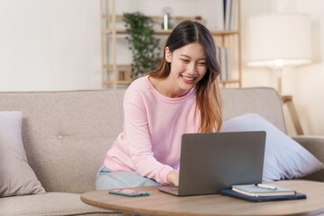 Happy young attractive smiling asian woman enjoying relax time at apartment.