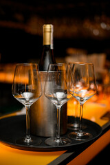 empty glasses and wine bottle stand on tray on the bar counter.