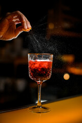Close-up of beautiful glass with cocktail on bar and droplets of citrus zest around it