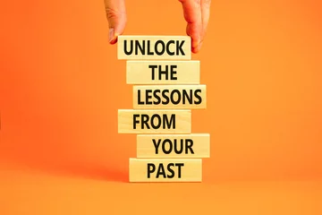 Foto op Canvas Lessons from your past symbol. Concept words Unlock the lessons from your past on wooden blocks. Bussinesman hand. Beautiful orange background. Business and lessons from your past concept. Copy space. © Dzmitry