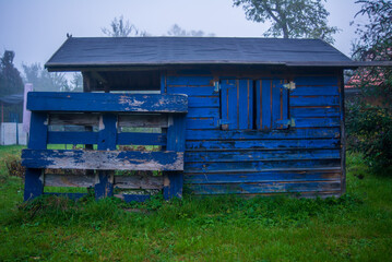 Old playhouse with chipped paint in a backyard in autumn