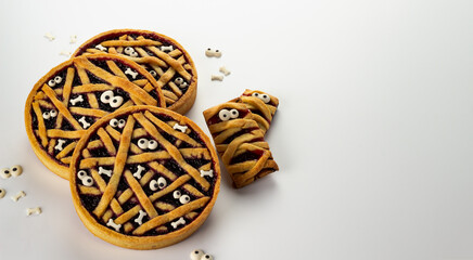 Halloween shortbread cookies with cherry confiture. Tart with jam, decorated with sugar bones and eyes. Cookie is a mummy with eyes. Terrible sweets.
