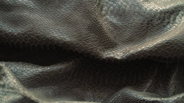 Close up of artificial grey leather-like reptile fabric snake or crocodile rotate in circle. Textile, material, cloth. Concept of production of shoes, bags. Textile industry