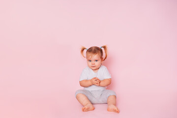 a two-year-old beautiful girl looks skeptical, isolated on a pink background. A look full of doubt. Distrust. Cheating a child. A bad joke.