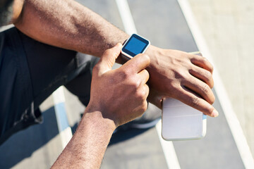 Hands of young black man sitting on staircase and checking or noting time on wristwatch before outdoor sports training or jogging