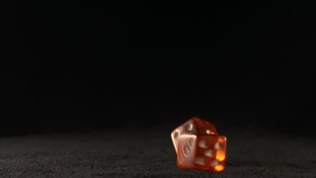 Two red dice thrown on a black casino table they are slowly turning in the air falling and rolling on the table in slow motion rolled a five and a three translucent red color illuminated Full HD 1080p